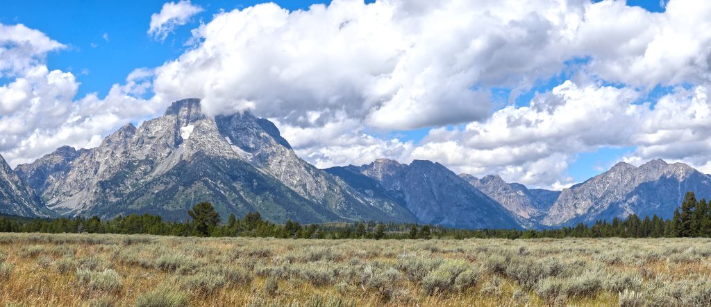 A Sunny patch highlights the Grand Teton (left). The flat valley of Gros Ventre meets the Teton range erupting straight up from the western edge. You can see the small glacier nestled into a cleft in the mountain.