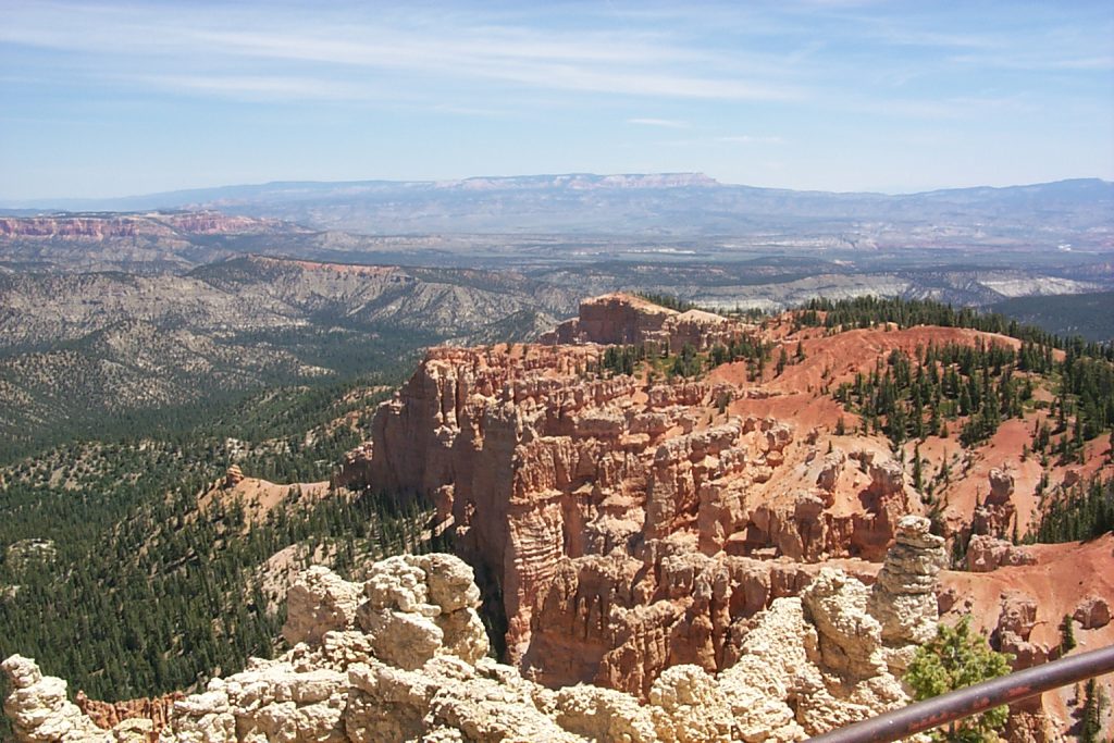 This is a view of the lower parts of Bryce taken from high on the Paunsaugunt plateau. The pink mesa seen at the top left is boat mesa which is recognisable anywhere in the park. In the far distance on the horizon in the centre is the Aquarius plateau whose tip is named Powell Point after the famous explorer. This feature dominates the landscape of the whole area!